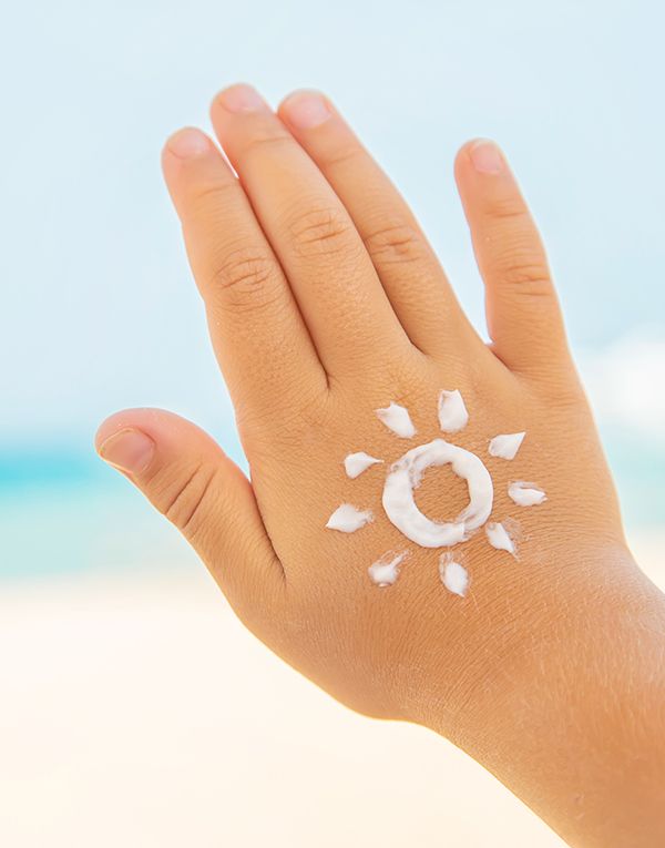 Una mano de un niño con protector solar haciendo el dibujo de el sol. Cremas solares de dermocosmética.